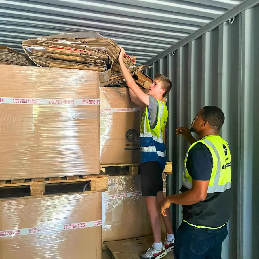 Books2Africa volunteers loading cartons of donated books into a shipping container