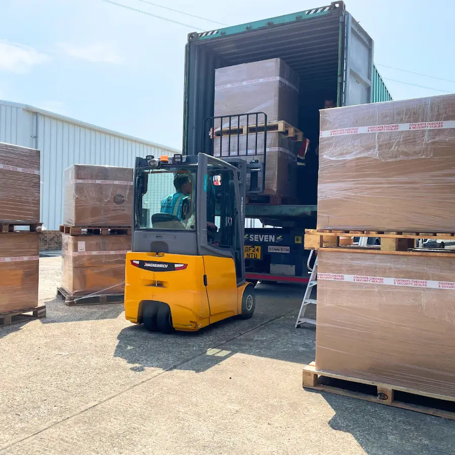 Forklift loading pallets of donated books into a shipping container