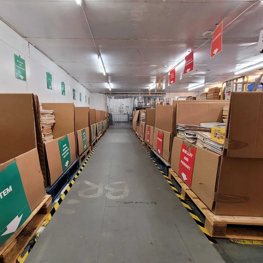 Aisle of cartons filled with sorted donated books at the Books2Africa Processing Centre in Canterbury