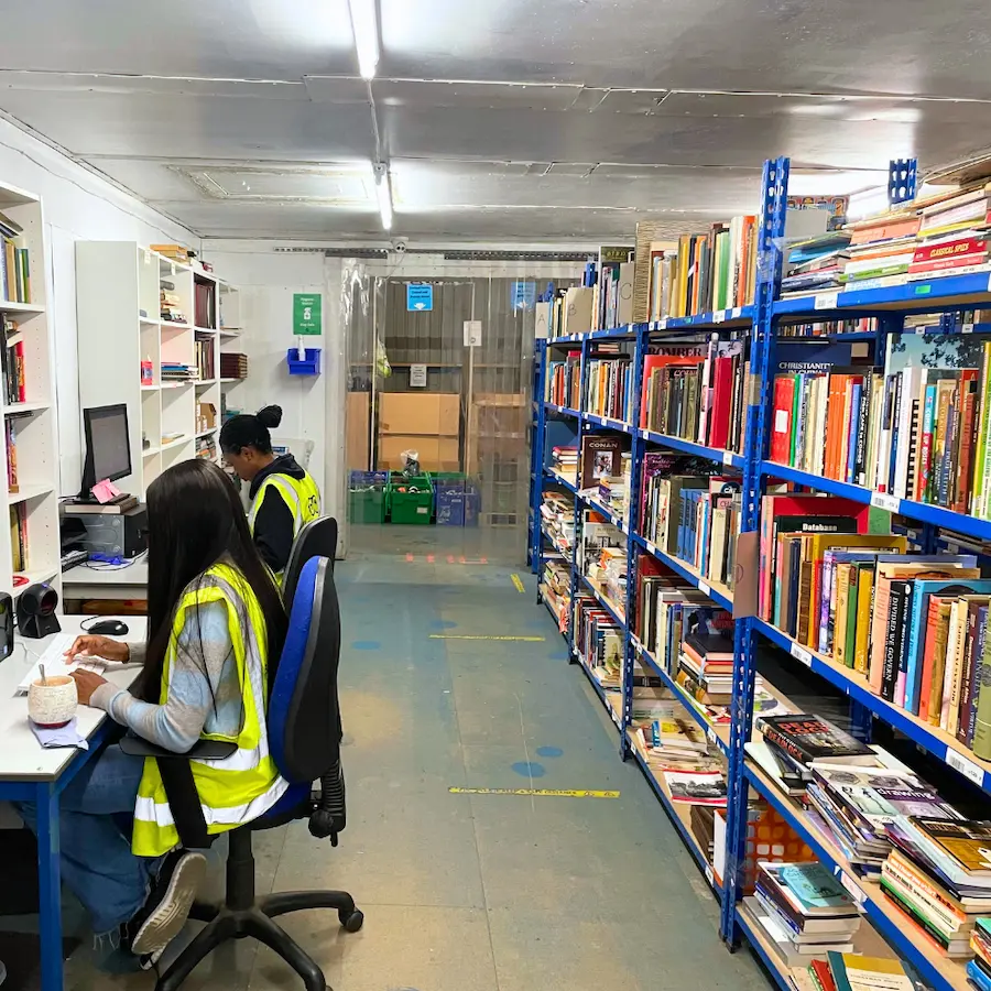 Books2Africa staff working at computers beside shelves of donated books